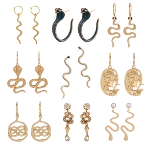 Detailed grid of nine assorted gold snake and Medusa drop earrings with crystal accents