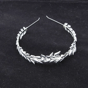 Detail of silver leaf bridal headband with metallic olive branch texture on black background