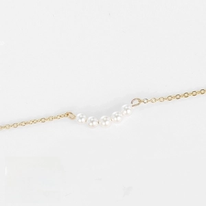 Détail du collier en acier 316L avec cinq perles blanches sur une chaîne dorée de 38+5cm