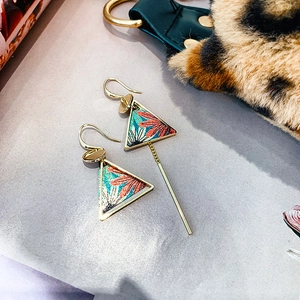 Detail view of asymmetric gold triangular earrings with vintage floral embroidery insets