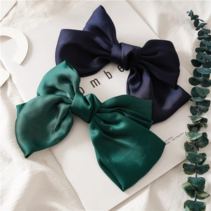 Detail of navy blue and dark green satin bow hair clips on elegant magazine layout