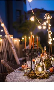 Nahaufnahme eines antiken Eisen-Kerzenhalters mit warmen orangefarbenen Kerzen im Garten
