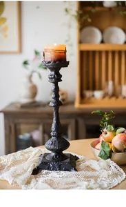 Nahaufnahme von Vintage-Gusseisen-Kerzenständer mit brennender Stumpenkerze auf dem Tisch