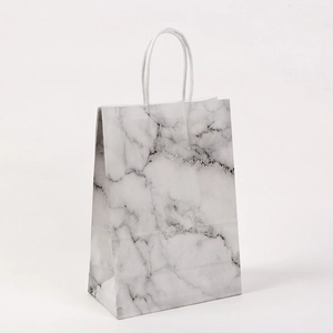 Detail of marble pattern paper bag with white rope handles on plain background