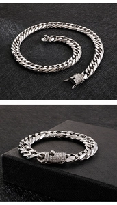 Close-up of silver Cuban link bracelet with a pavé-set diamond clasp on black texture
