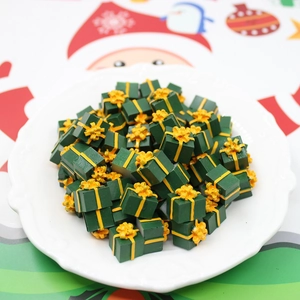 Macro detail of miniature green resin gift boxes with yellow bows for DIY Christmas crafts
