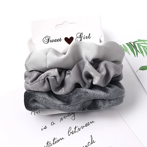 Close-up of grey fabric scrunchies set in satin and velvet textures on branding card