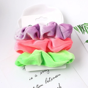 Three-piece velvet scrunchie set in purple, pink and green on a display card