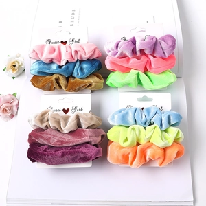 Flat lay of velvet scrunchies set in various candy colors with floral decoration