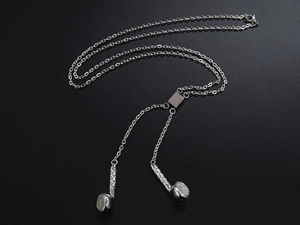 Detailed close-up of silver headphone pendant necklace made of stainless steel on black