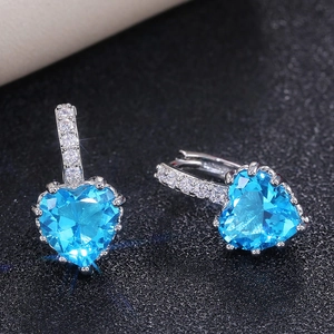 Macro shot of sky blue heart crystal earrings with sparkling diamond-set hooks in white gold