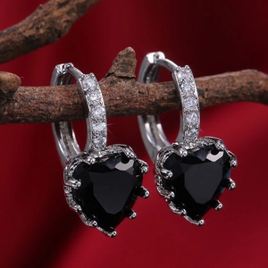 Detailed close-up of heart-shaped black zircon earrings with clear stone pavé on dark velvet