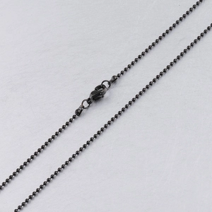 Close-up of black beaded necklace chain with a secure lobster clasp on grey surface