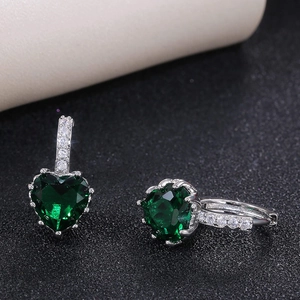 Macro shot of emerald green heart-shaped earrings with white zircon accents in silver setting