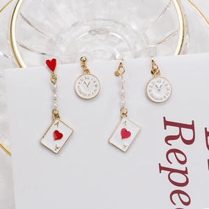 Close-up of asymmetrical earrings featuring Alice clock, card suit and white pearls