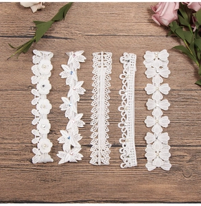 Flat lay of five distinct white lace headbands with faux pearls and rhinestones on wood