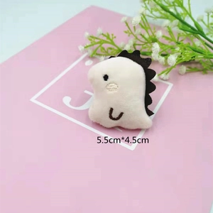 Detailed view of a mini plush dinosaur accessory with embroidery, measuring 5.5cm x 4.5cm