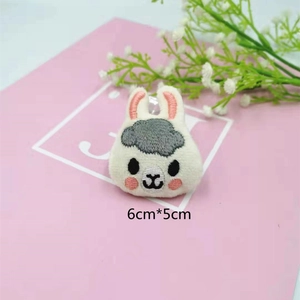Detailed view of plush alpaca patch with size 6cm x 5cm on pink decorative background