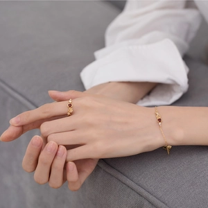 Detail of 925 silver 9K gold plated garnet flower bracelet and ring on a model's hand