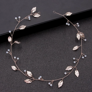 Handmade golden bridal hair vine with metallic leaves and light blue beads on a black box