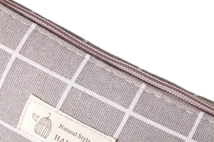 Detail of gray checkered fabric texture with brown zipper and woven label on a storage bag