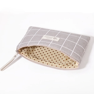 Detail view of large grey checkered cosmetic bag showing brown polka dot inner lining