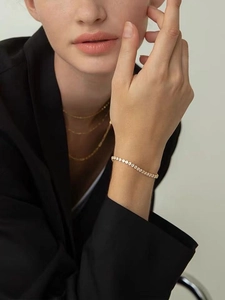 Close-up of elegant gold tennis bracelet and layered necklaces on a female model