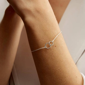 Détail d'un bracelet en argent avec cercles entrelacés porté délicatement au poignet