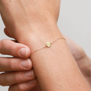 Close-up of golden stainless steel bracelet with hammered round charm on a woman's wrist