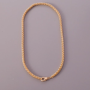 Close-up of golden geometric woven link necklace with a secure lobster clasp