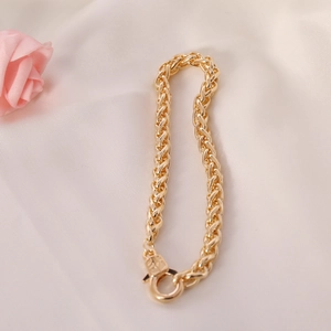 Detailed close-up of a gold-plated twisted rope chain bracelet on white silk fabric