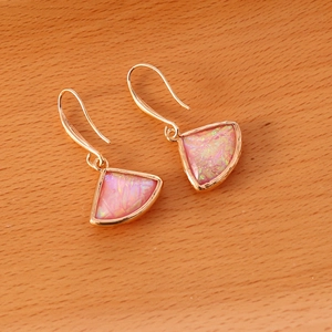Pink fan-shaped natural stone earrings with gold hooks on a minimalist wooden background