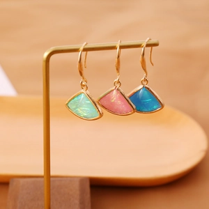 Detail of fan-shaped drop earrings in mint green, pink, and blue with gold frames