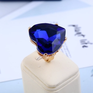 Macro shot of a deep blue heart-shaped gemstone ring with a golden claw setting