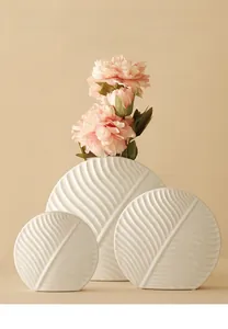 Detailed close-up of three white leaf-patterned ceramic vases with realistic pink flowers