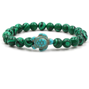 Detail of beaded bracelet featuring green malachite texture beads and turquoise turtle charm