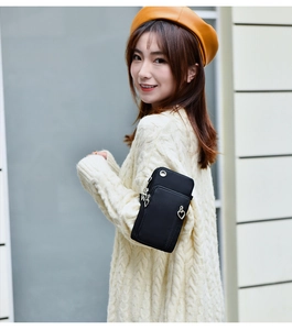 Détail du petit sac bandoulière noir avec fermeture cœur et trou pour les écouteurs