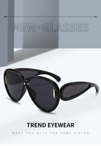 Détail de lunettes de soleil noires oversize avec branches évidées et accents dorés