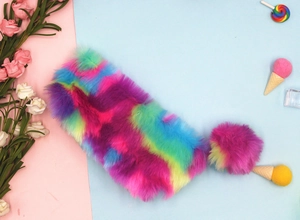 Dettaglio dell'astuccio in peluche arcobaleno con un morbido portachiavi a pompon colorato