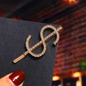 Close-up of golden dollar sign hair clip with sparkling rhinestones on black card