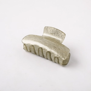 Detail showing the champagne gold claw clip with a refined brushed texture finish