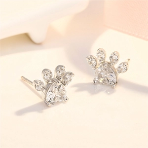 Macro detail of paw-shaped stud earring with heart-shaped crystal and silver finish