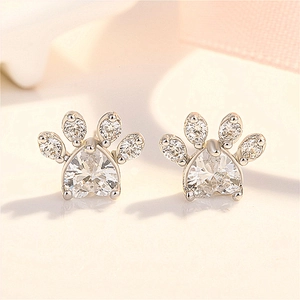 Macro shot of silver cat paw stud earring with heart-shaped crystal and cubic zirconia
