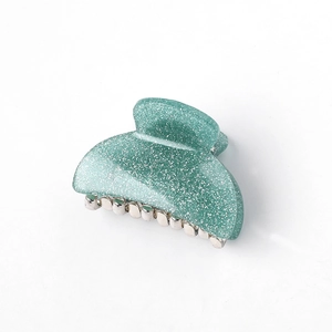 Detail shot of a green glitter acrylic hair claw clip with a durable metal spring