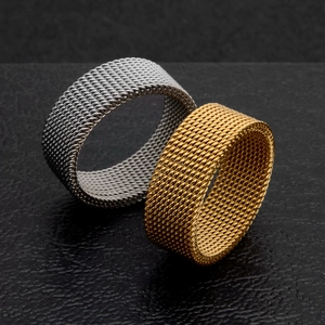 Detailed macro view of gold and silver flexible mesh rings on black textured surface
