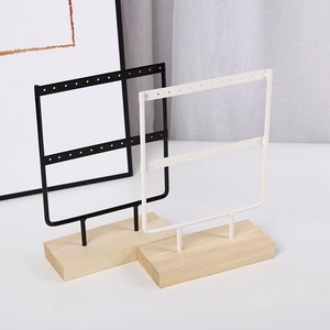 Close-up of black and white metal earring stand with double-tier pine wood base