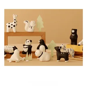 Variety of cute ceramic animal figurines including panda and penguin on a wooden display