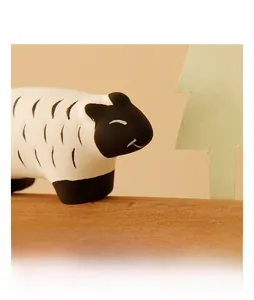 Close-up of a cute ceramic sheep figurine with a healing smile on a wooden base