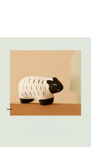 Close-up of minimalist black and white ceramic sheep figurine on wood base decor