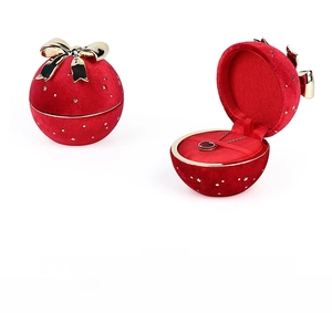 Detail of red velvet spherical jewelry box with gold stars and metallic bow